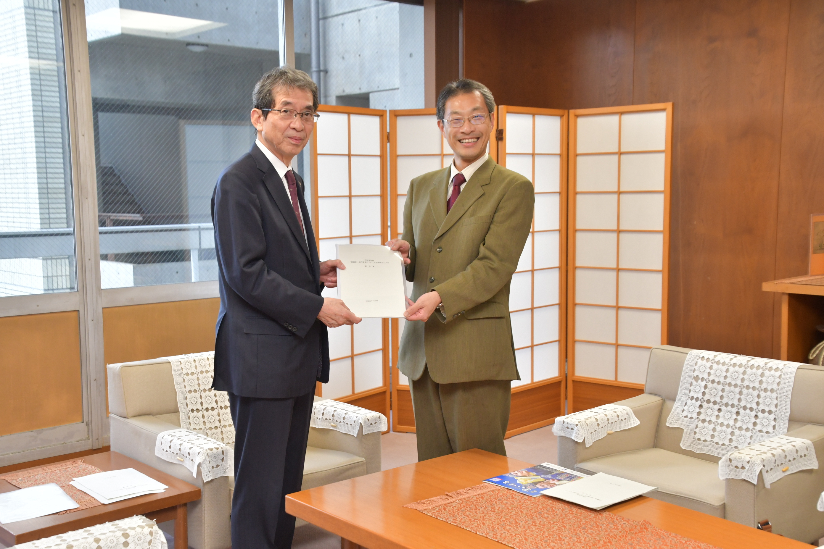 窪田塾長から市長への報告書手交の様子